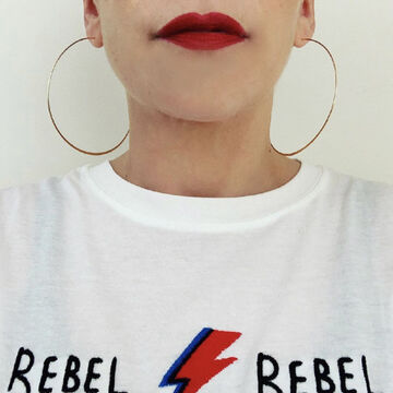 Selfie of L Vinebaum, an adult person with a fair skintone, with half of their face out of frame. They're wearing a t-shirt that says "REBEL REBEL."