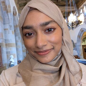 Selfie of Aisha Valiulla, an adult person with a medium-light skintone and wearing a hijab. 