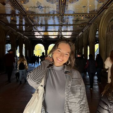 Victoria Trakas, an adult person with a fair skintone, standing under an ornate ceiling. 