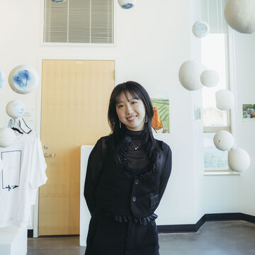 A person standing in front a wall with white sculptural installations.