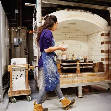 Ceramics student walks piece to kiln