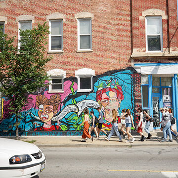 A group of students exploring Pilsen neighborhood in front of a mural.
