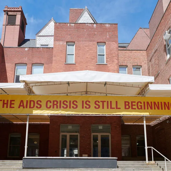 Photo of exterior building with banner reading "The AIDS Crisis is Still Beginning"