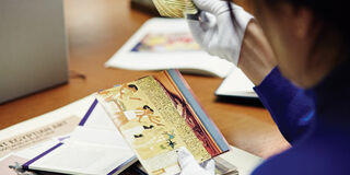 A person wearing white gloves handling images of Egyptian hieroglyphs.