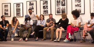 A photo of students sitting in chairs passing around a microphone