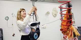 A photo of a woman interacting with an art installation in a gallery setting