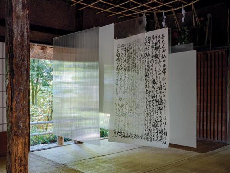 Pieces of paper hang from a rack in a traditional Japanese interior