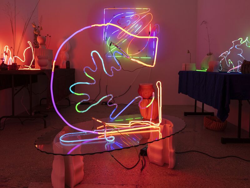 A circular neon work displayed on a table at a gallery.