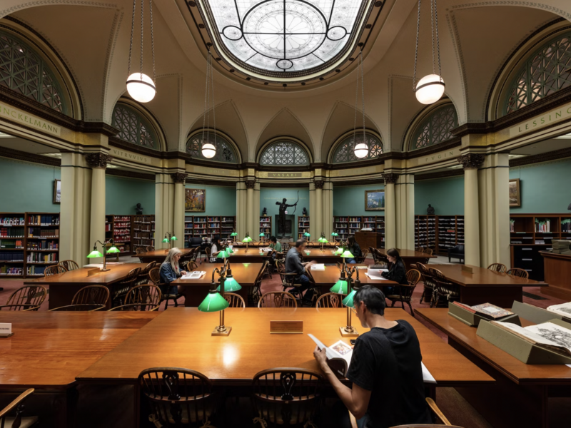 Person reading book sitting at table in large library