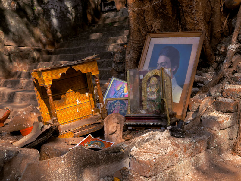 Various Indian artifacts and framed photos on top of brick. 