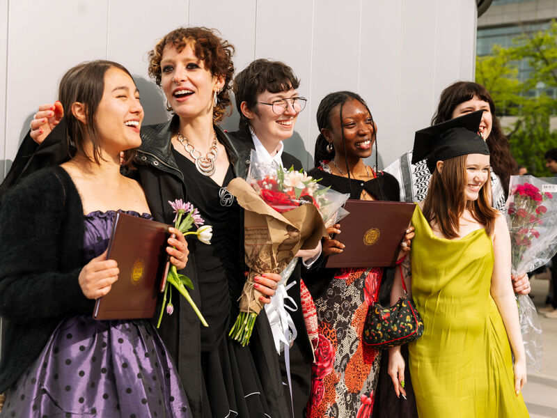 A group of six recent graduates, varying in ethnicity and gender, posing for photos while holding degrees and flowers. 