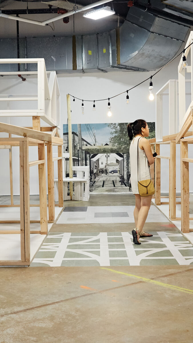 A student walking through a large scale installation using natural and white wooden planks.