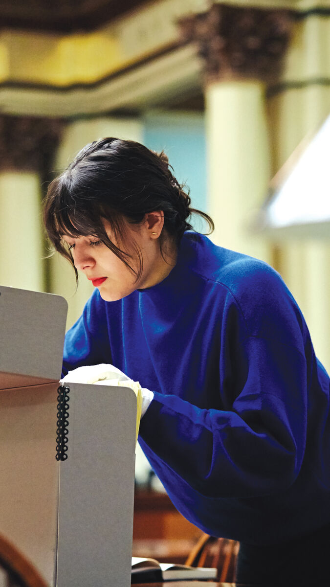 A student looking through a large file in the library.