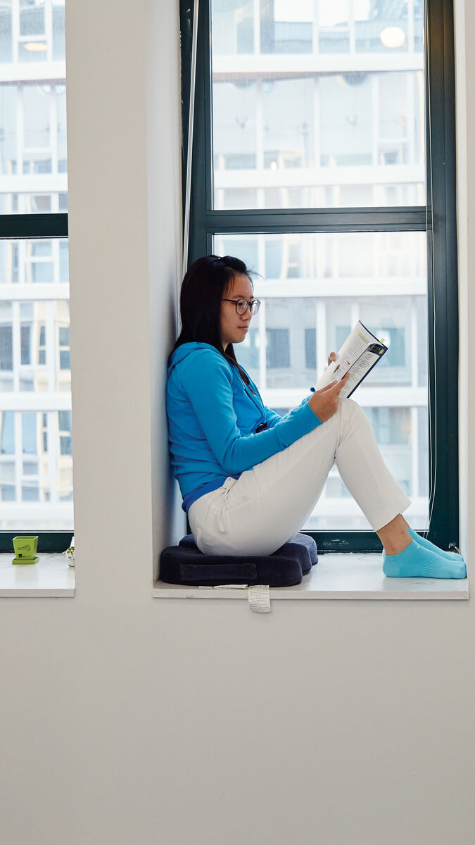 A student sits in a windowsill reading a book in the 162 North State Residence Hall.