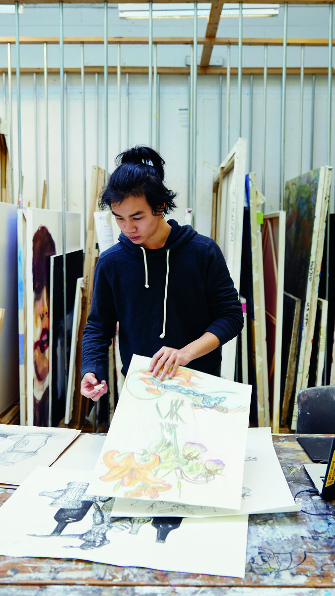A person in a studio looking through pieces of art. 