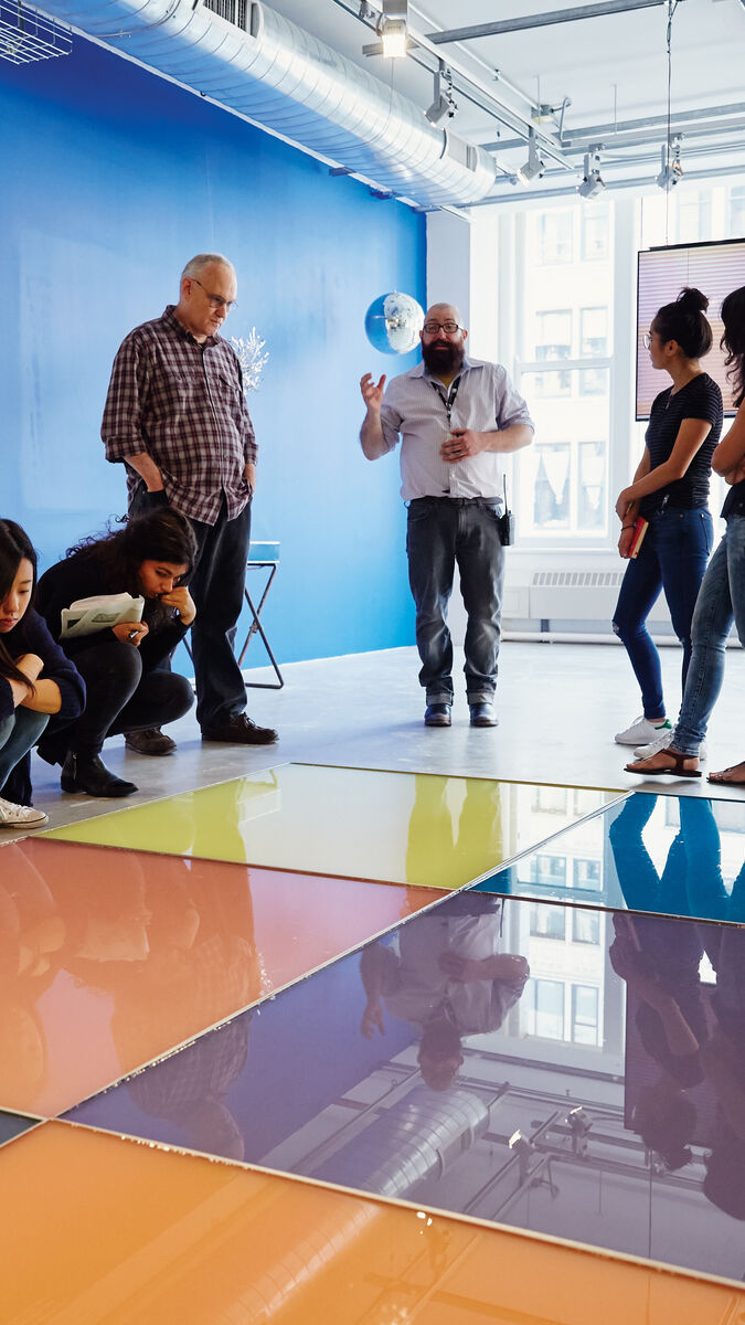 An image of some students observing a large piece of art on the floor in the School of the Art Institute of Chicago's gallery space. 