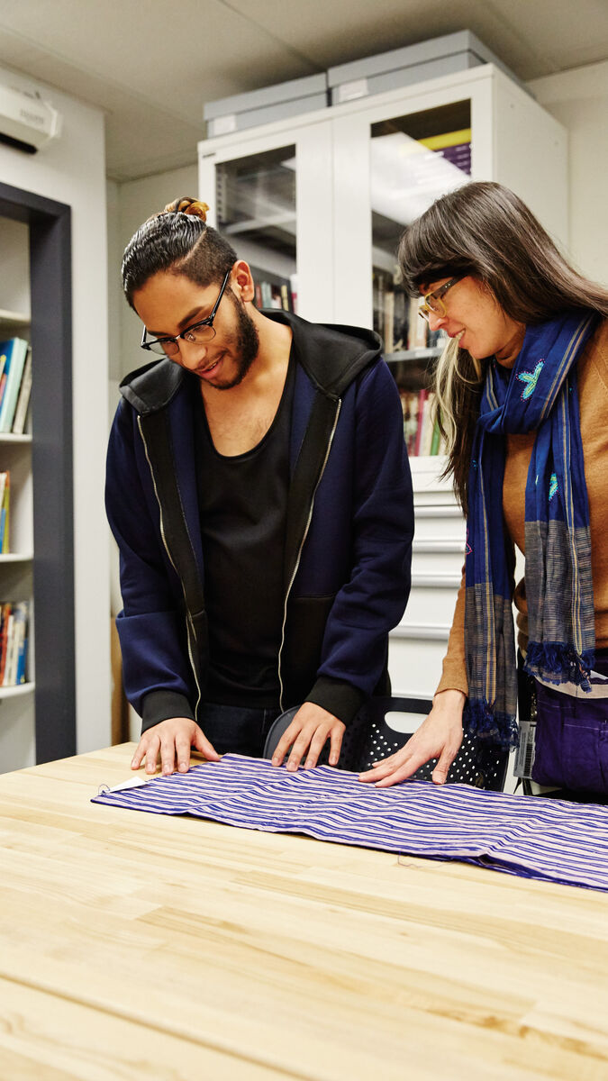 Two students looking at a piece of fabric on a table. 