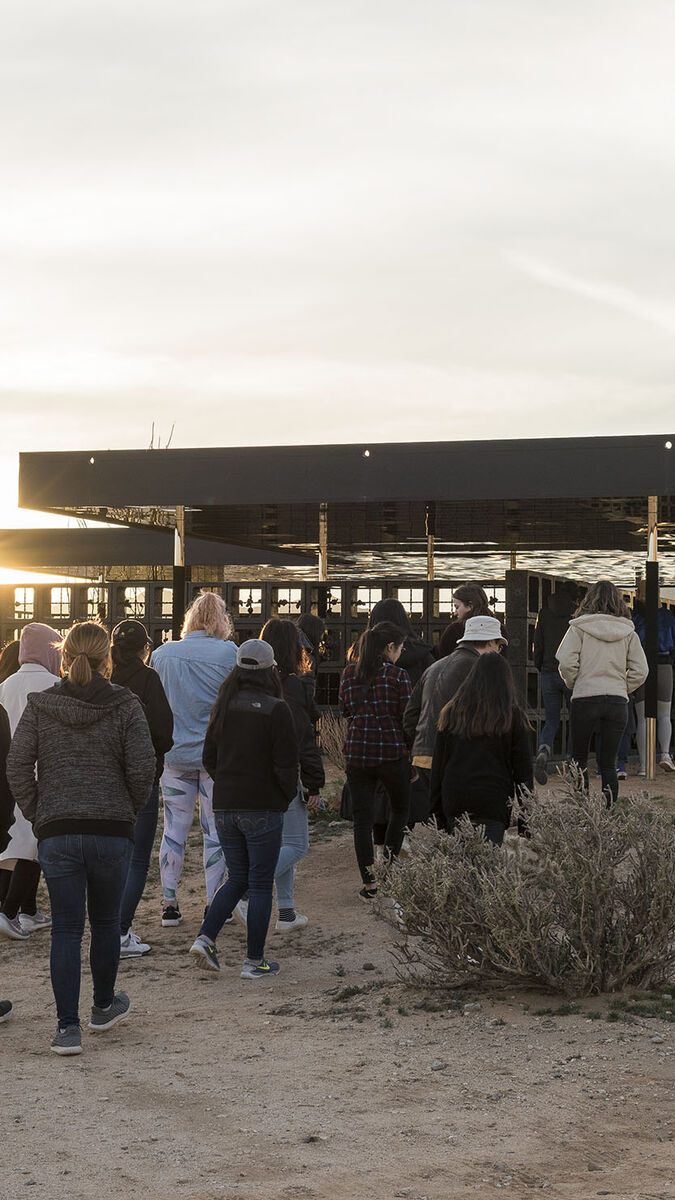 Students walk into a building in a desert