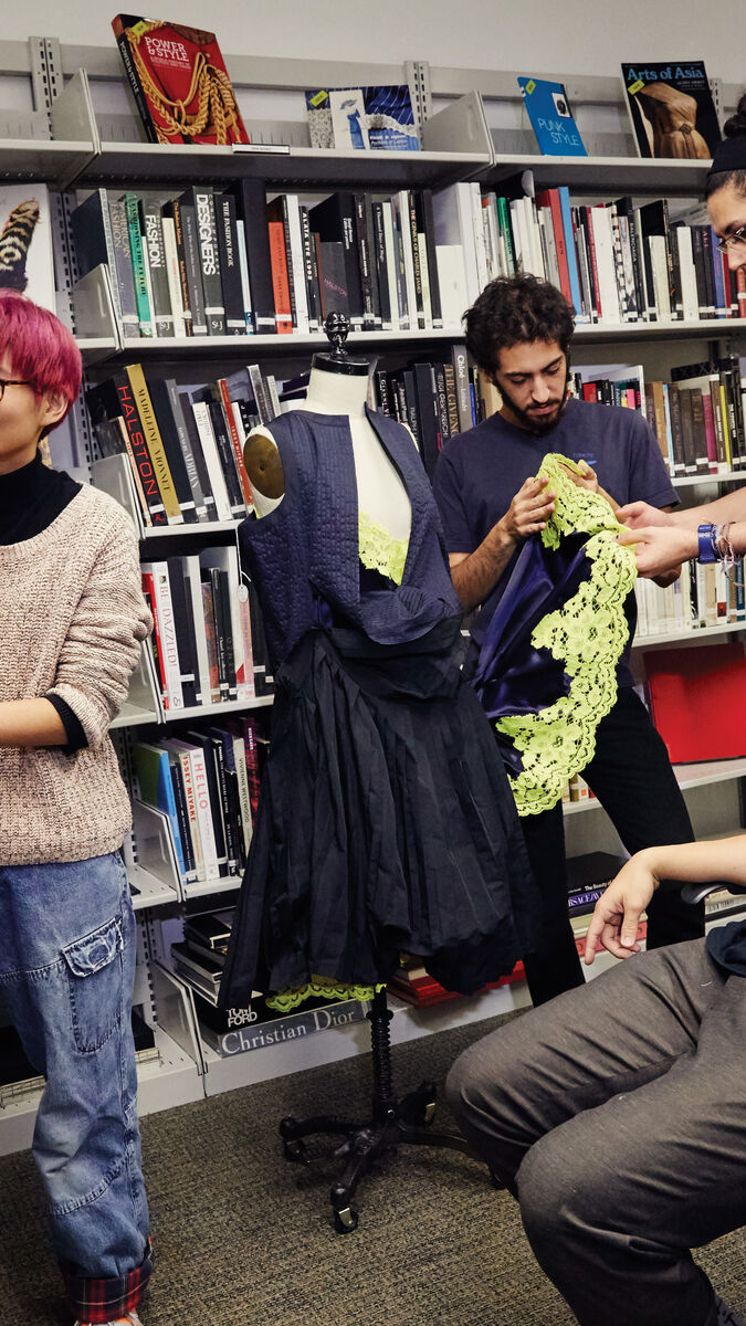 Four SAIC students working and examining garments in the fashion resource center.