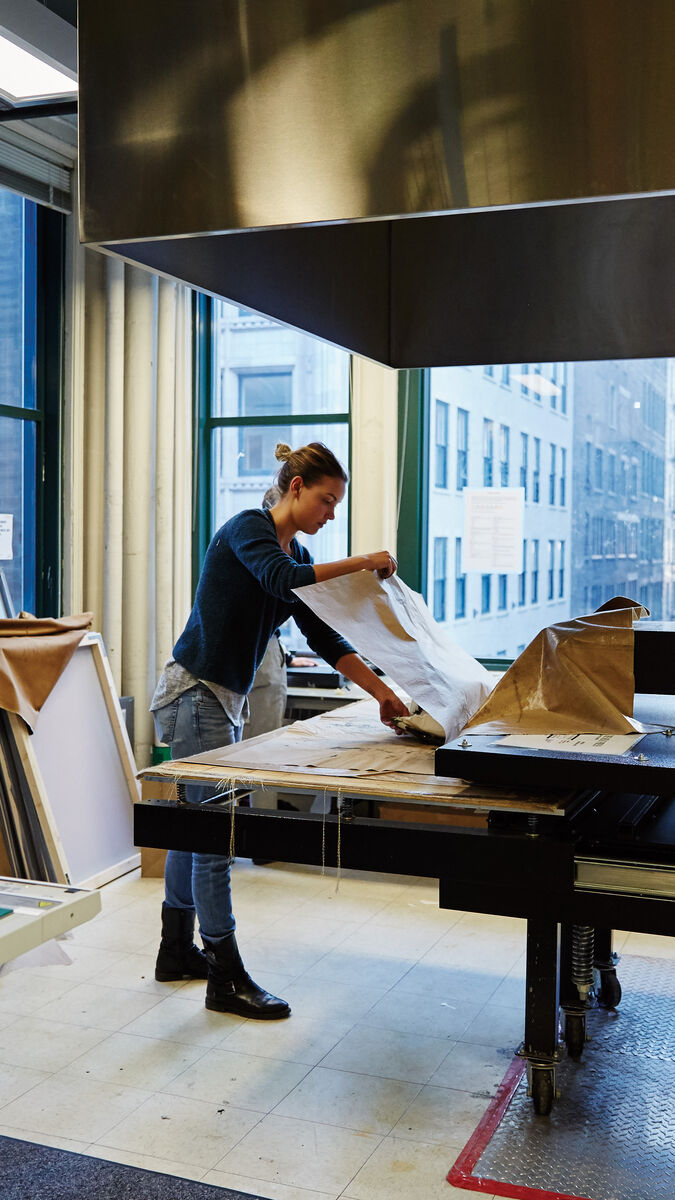 A student wrapping a piece of art at a workstation.