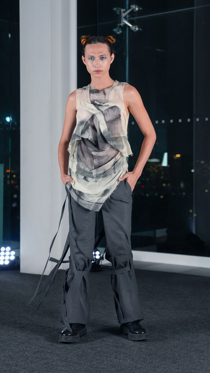 A model wears structured pants and a gauzy, abstract shirt 