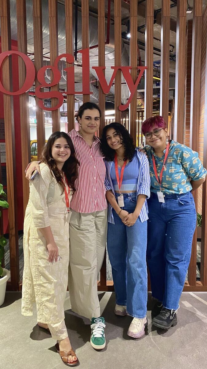 Four adults of varying ethnicities and genders stand in front of a sign that reads "Ogilvy."