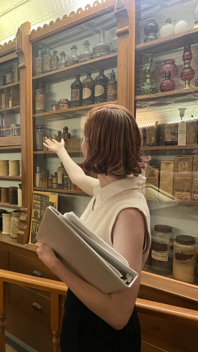 A person gestures toward a glass museum display. 