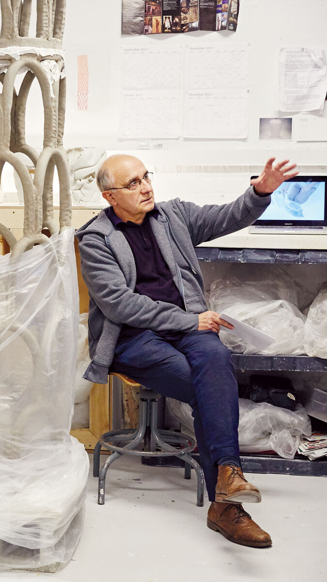 A faculty member sits with a student in an art studio.