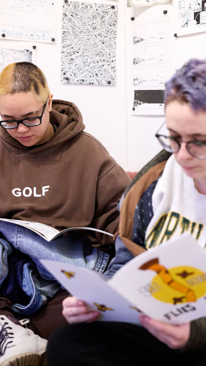 Two students viewing booklets from an exhibition. 