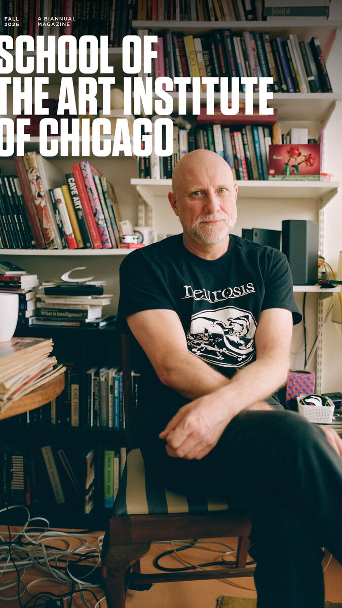 An artist poses on a chair in his office