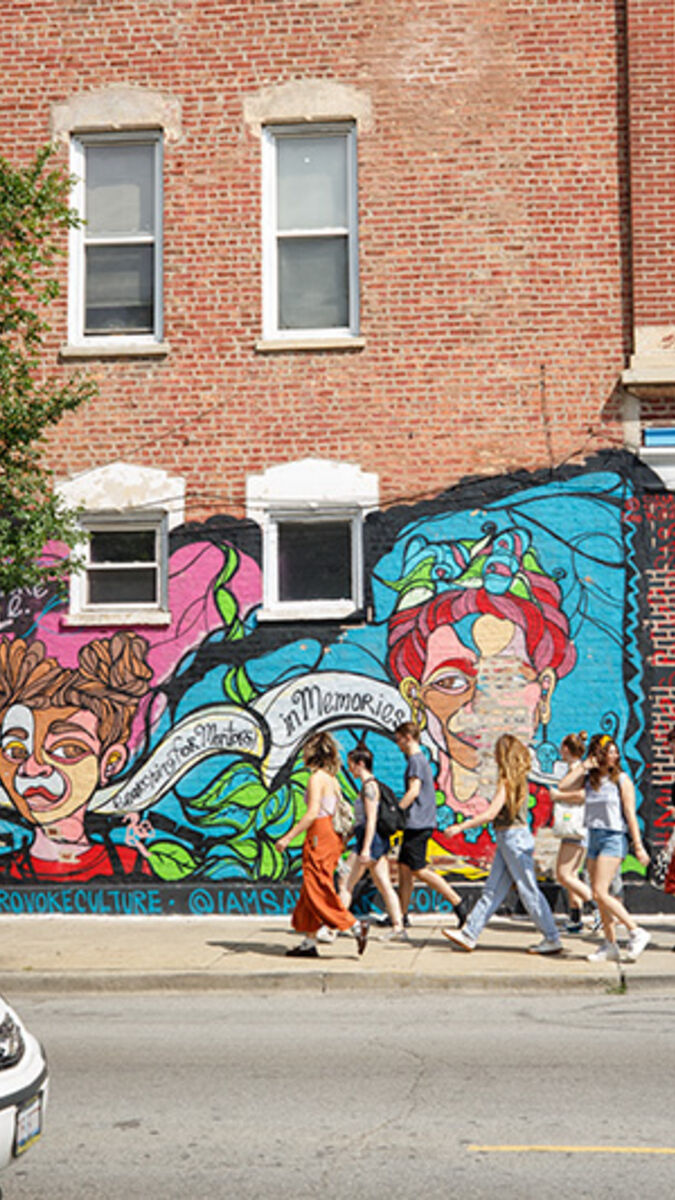 A group of students exploring Pilsen neighborhood in front of a mural.