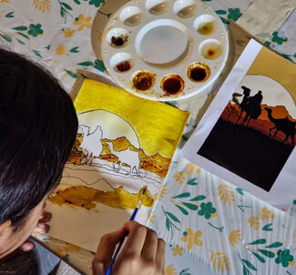 A young girl painting a desert landscape with spices on a table, focused and creative