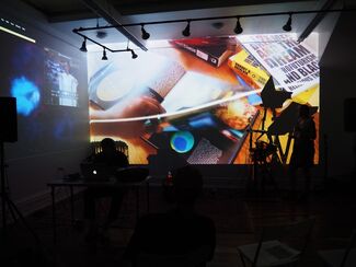 Still of a performance piece by Fleming and Hunter Whittaker-Morrow that includes colorful projections in a dark room