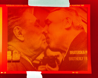Two white politician men kissing with an orange overlay. 