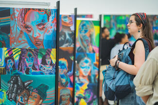 Person viewing a series of highly saturated portraits of Black women rappers by Caitlin Cherry.