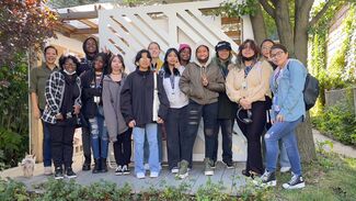 A group of CAAP students stand outside in front of a while facing the camera.