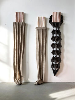 Three staggered sculptures of varying shapes and colors. 