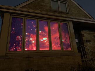 Light projection installation by Valerie Xanos viewed through an exterior window of a house. 