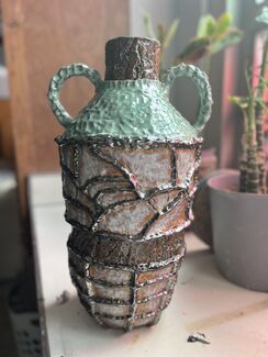 A ceramic vessel with two handles and a green lid.