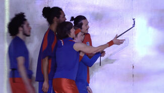 Five performers in blue and red outfits on stage.