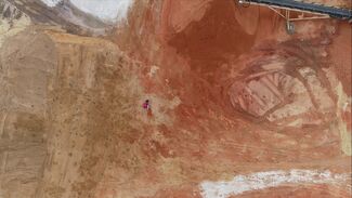 Drone image taken from above of a person lying down against a brown backdrop.