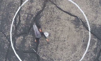 An image shot from above of a performer on the ground with their legs raised in front of them.