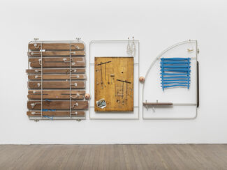 Three metal and wood sculptural installations hanging on a white wall.