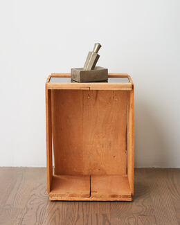 A gray perfume bottle placed on a wooden crate.