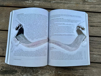 A book sits open on a table, with an illustration of two cows in addition to text.