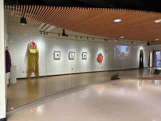 Clothing and artwork hung on the walls in a gallery.