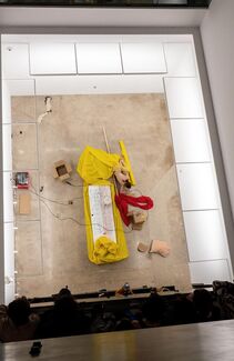Aerial view of a person laying among yellow fabrics, pillows, and cardboard. 