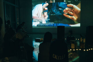 Silhouetted people viewing a projection of Camille Casemier's performance in a gallery space. 