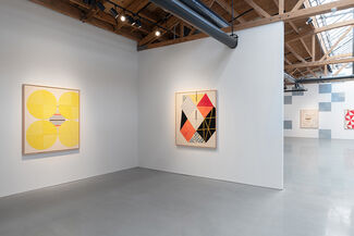 An installation view of an exhibition with colorful paintings on the wall.