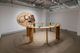 Painted eggshells by Emily Miller displayed on a round table, with a painting displayed in the background. 